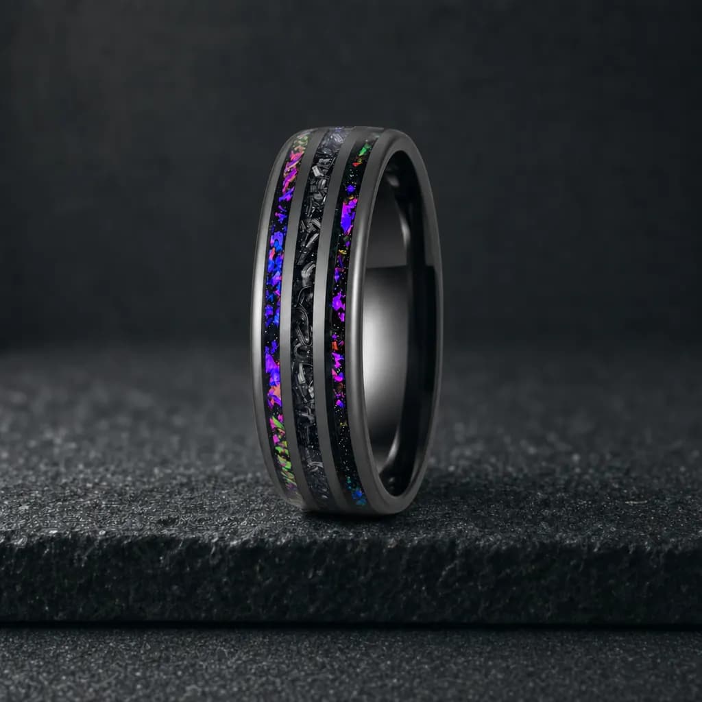 The Vertex, an 8mm polished tungsten carbide band in black, blue and green with a meteorite inlay, standing upright on a dark iron grey stone slab