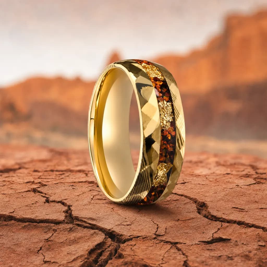The Fold, an 8mm faceted gold damascus steel band with a dinosaur bone inlay, standing upright on cracked red desert earth