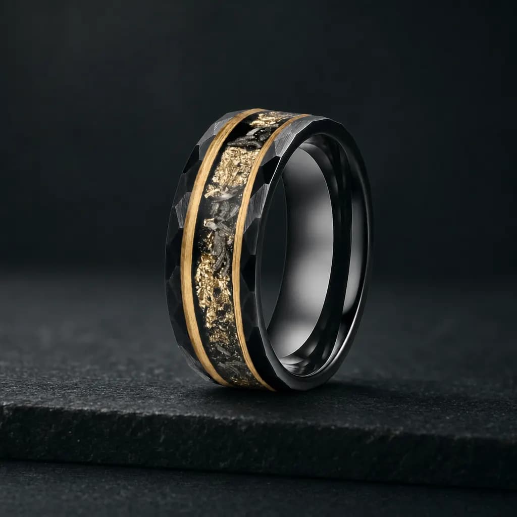 The Nebula, an 8mm faceted tungsten carbide band in black, gold and silver with a meteorite inlay, standing upright on a dark iron grey stone slab