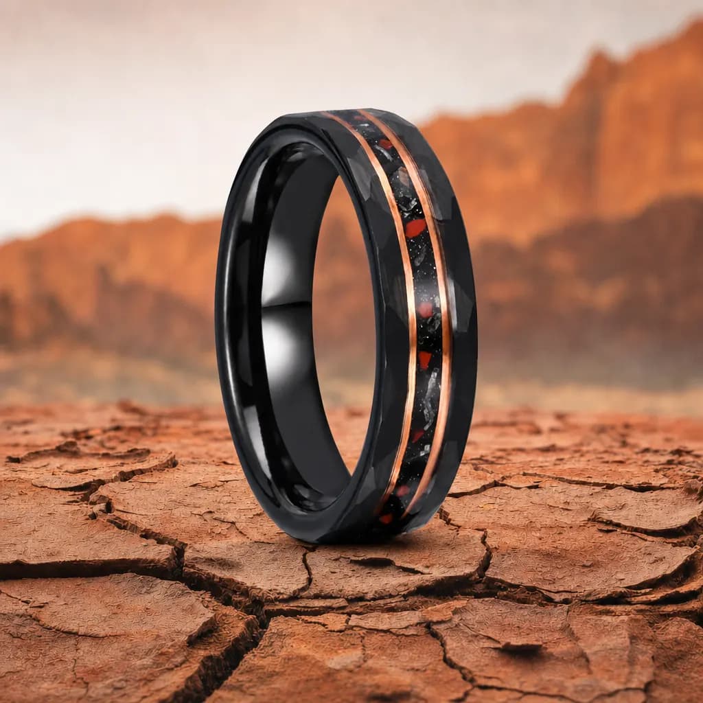 The Primeval, a 6mm faceted tungsten carbide band in black and rose gold with a dinosaur bone inlay, standing upright on cracked red desert earth