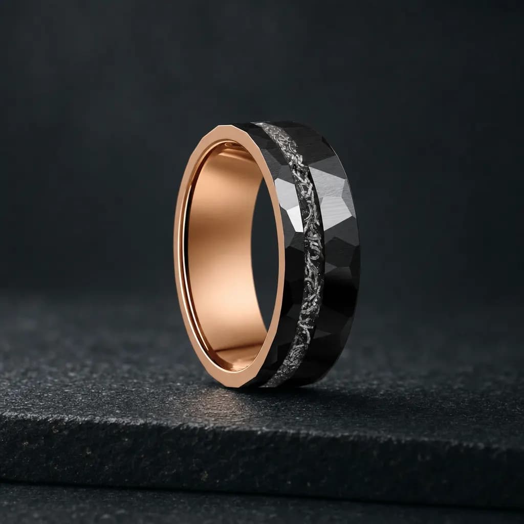 The Quasar, an 8mm faceted tungsten carbide band in black and silver with a meteorite inlay, standing upright on a dark iron grey stone slab